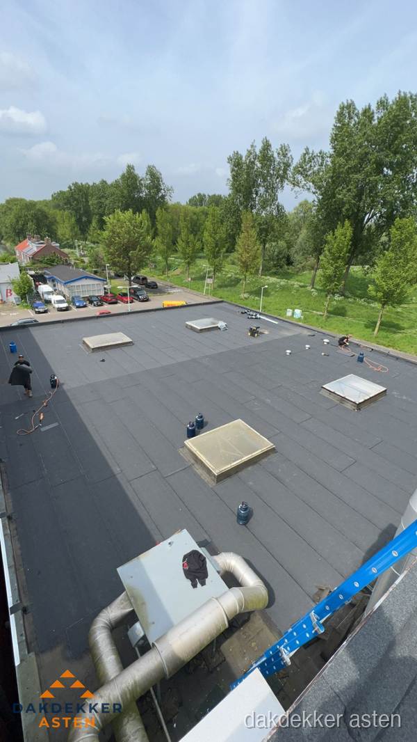 Dakdekker aan het werk op groot plat dak met bitumen in Asten
