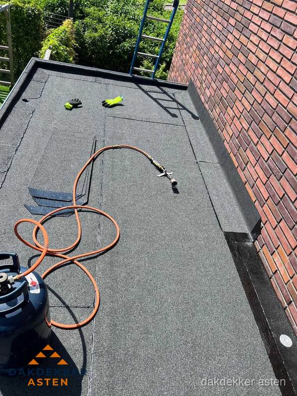 Plat dak met bitumen en brandgereedschap van dakdekkersbedrijf in Asten