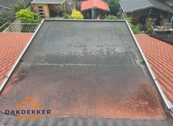 Verouderd plat dak met slijtage tussen schuine daken in Asten Verouderd plat dak met slijtage tussen schuine daken in Asten