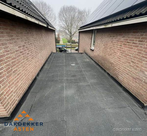 Plat dak met bitumen dakbedekking tussen bakstenen muren in Asten Plat dak met bitumen dakbedekking tussen bakstenen muren in Asten