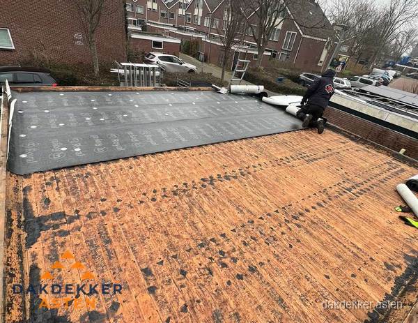 Dakdekker legt onderlaag op plat dak met houten constructie in Asten
